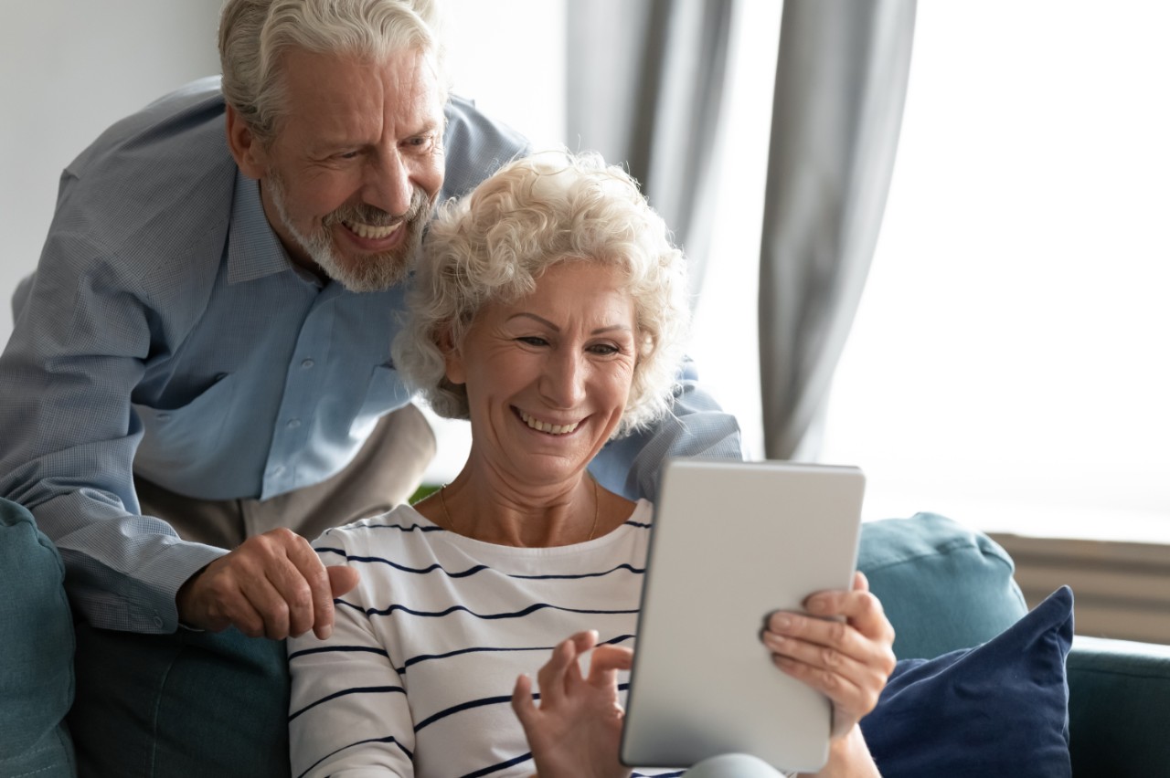 Elderly couple using a tablet and smiling