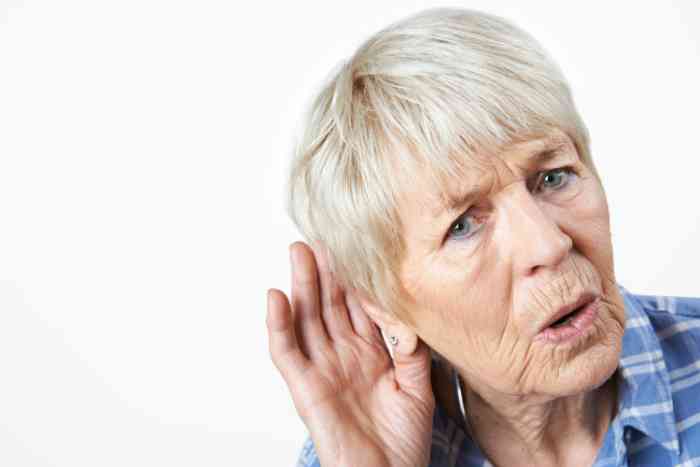 Elderly woman with a hand around her ear
